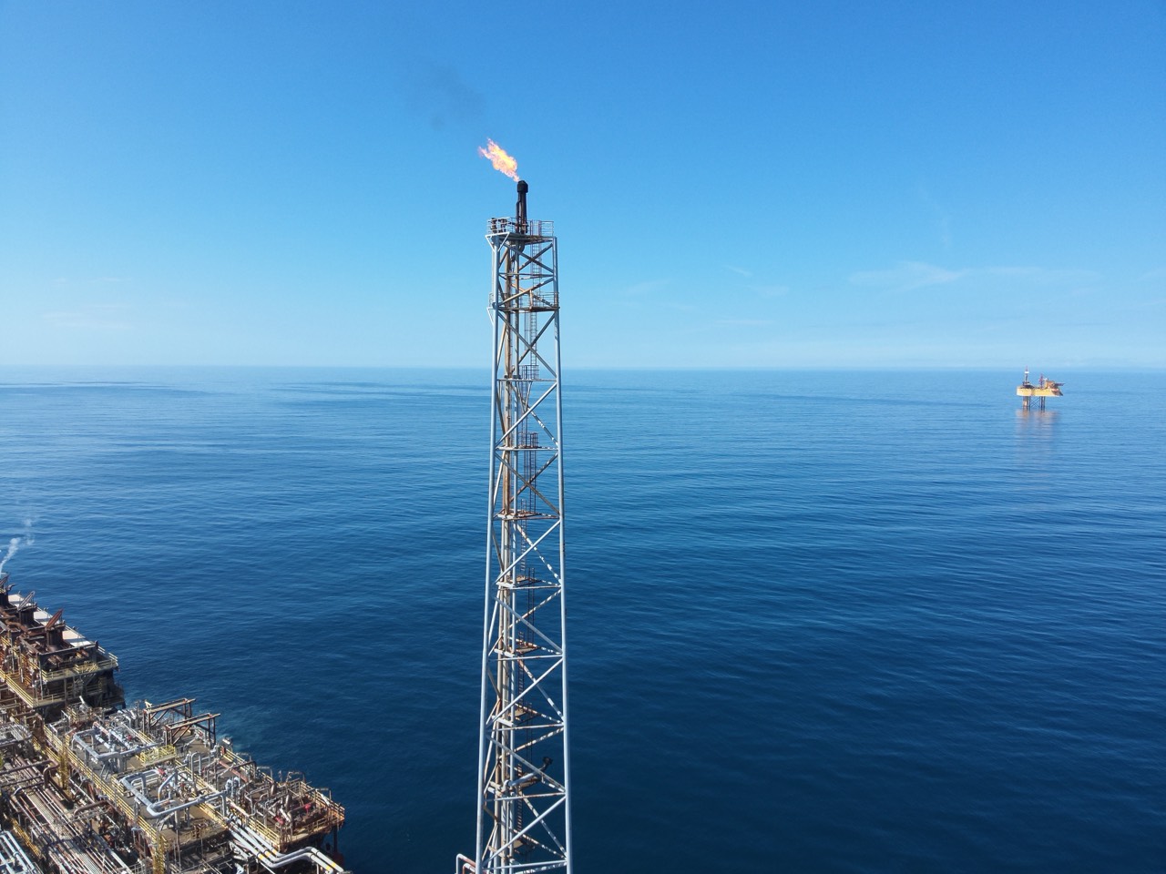 Aerial view of an offshore production platform and flare at sea