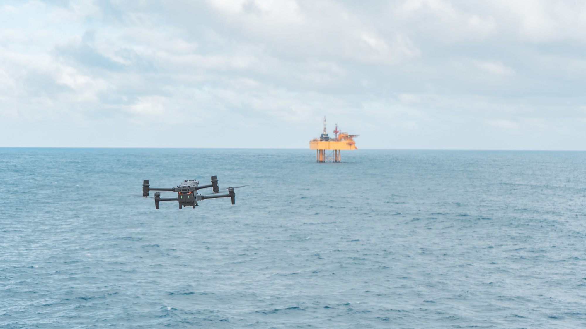 Inspection drone in flight over open sea beside an offshore platform