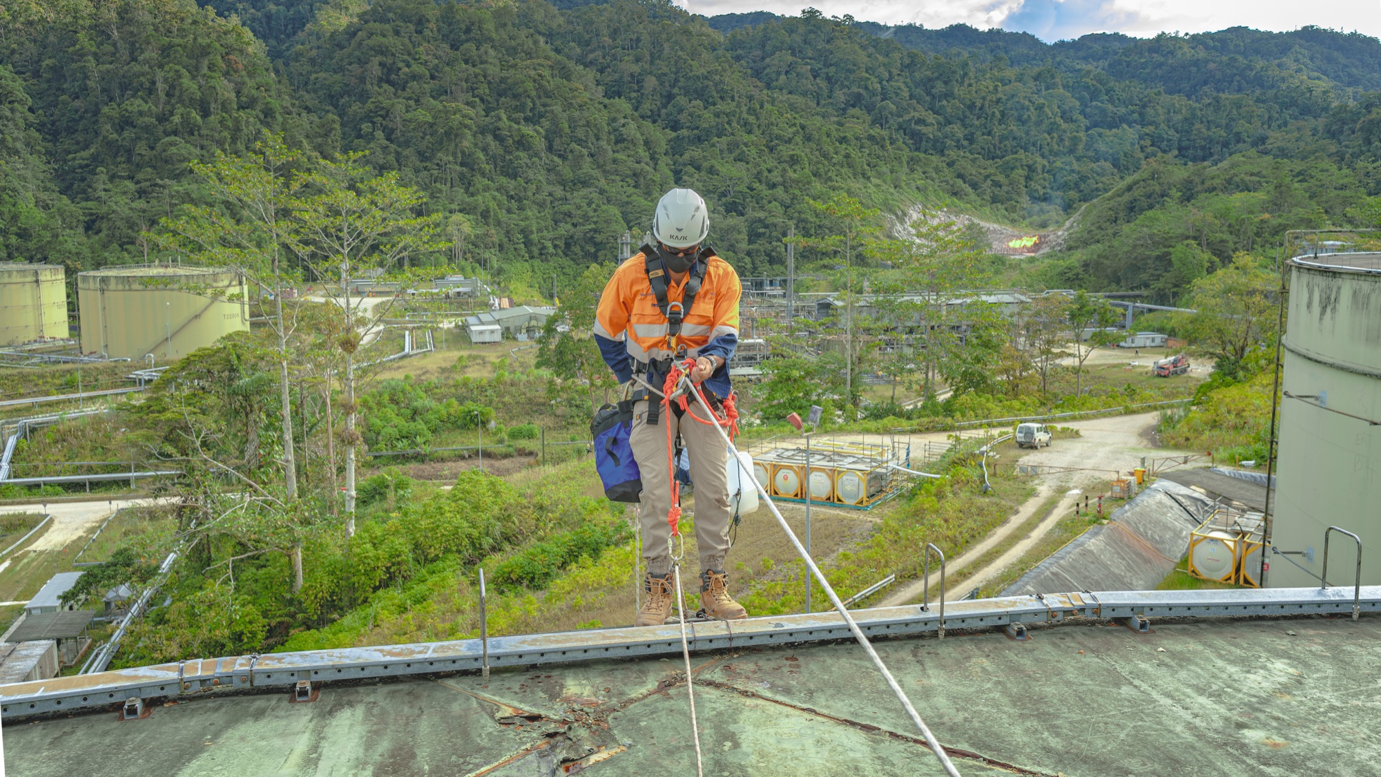 Rope-access technician descending the roof of a large storage tank