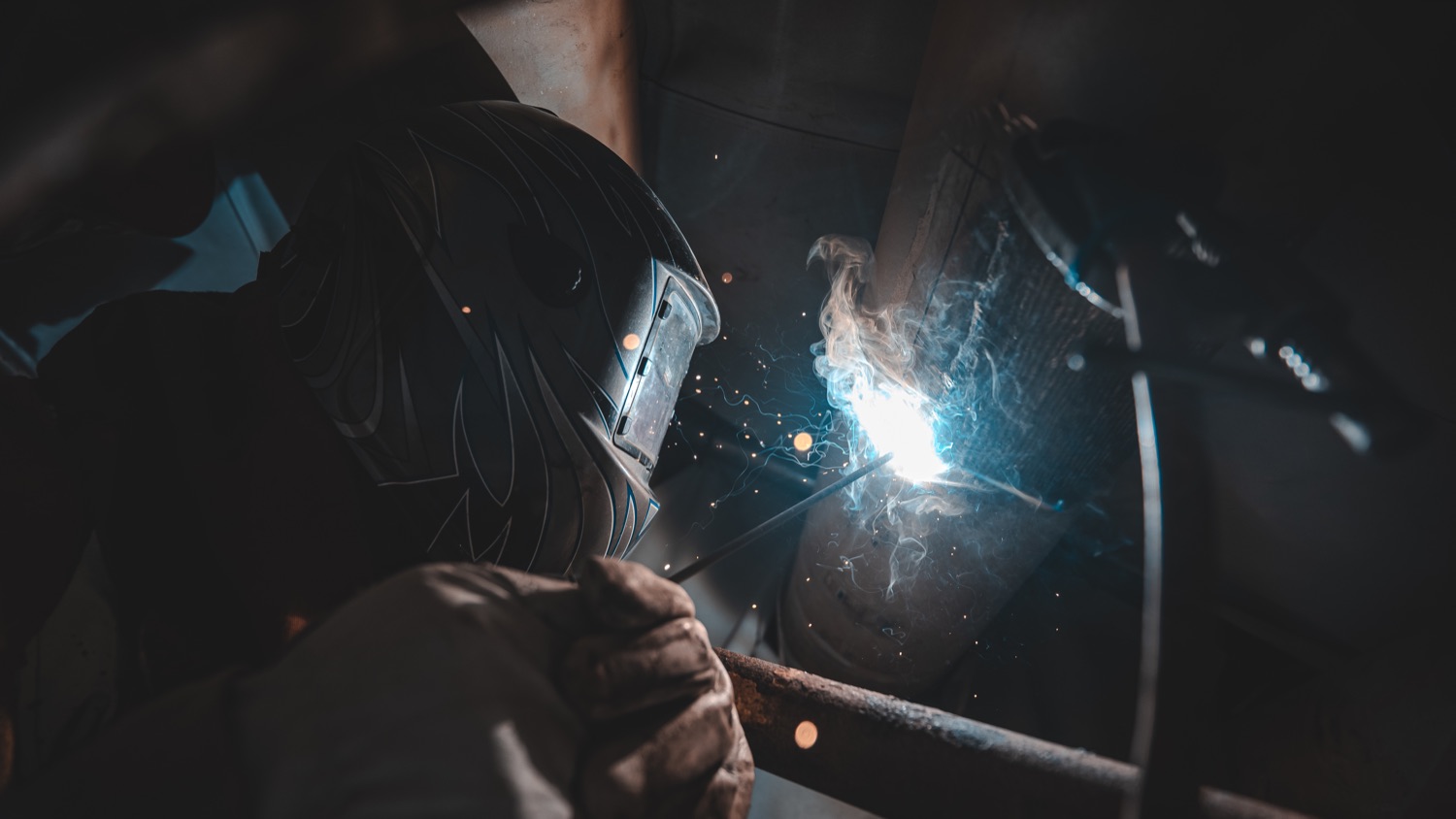 Welder striking an arc with sparks flying during a weld inspection